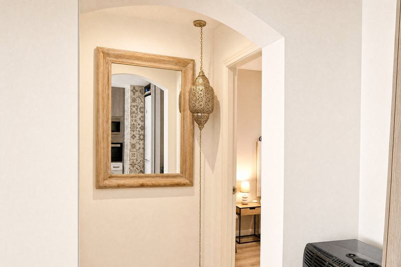 A bright hallway with an arch, a mirror and a lantern